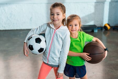 Front view of children smiling and holding balls in gymの写真素材