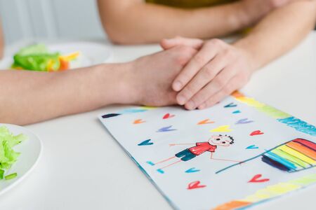 cropped view of homosexual men holding hands near drawing with lgbt flag