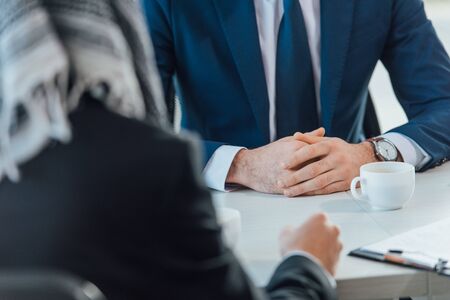 cropped view of businesspeople having meeting in office with coffee cupsの写真素材