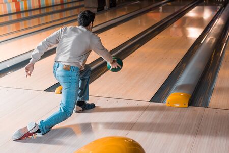 back view of young man throwing bowling ball on skittle alleyの写真素材