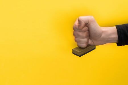 cropped view of man holding stamp isolated on yellow, quality concept