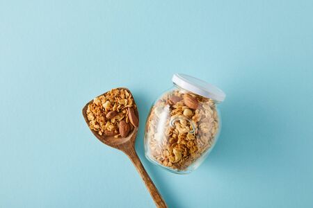 Top view of jar of granola with wooden spatula on blue backgroundの写真素材