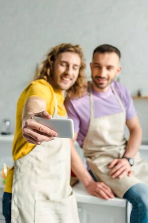 selective focus of homosexual men in aprons taking selfieの写真素材