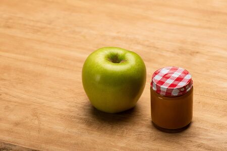 Jar of fruit baby nutrition with green apple on wooden backgroundの写真素材