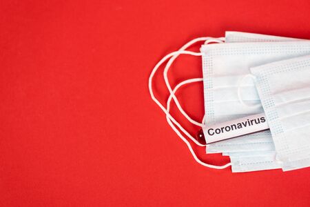 top view of sample with coronavirus lettering near protective medical masks on redの写真素材