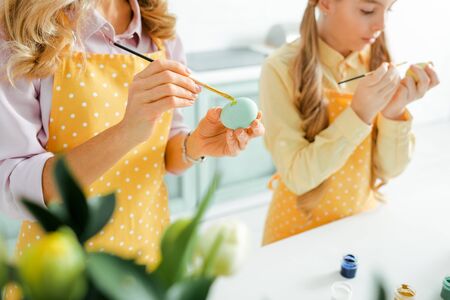 selective focus of daughter and mother painting easter eggs