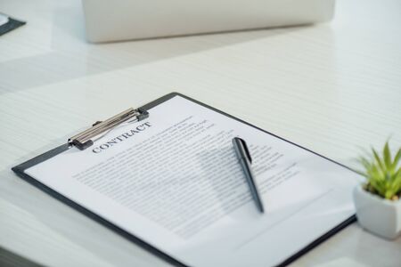 business contract on clipboard with pen on white table