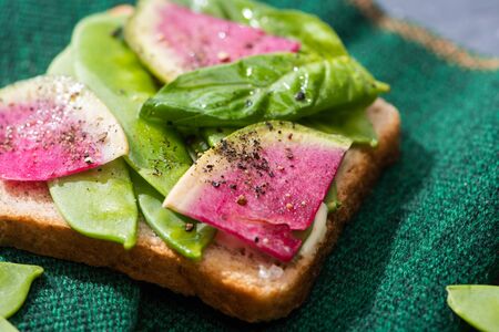 close up of toast with radish, green peas and basil on clothの写真素材