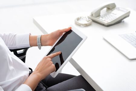 Cropped view of businesswoman using digital tablet with blank screen at tableの写真素材