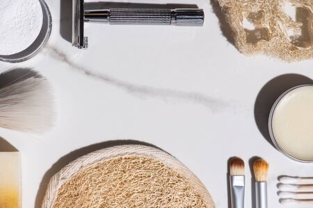 Top view of cosmetic brushes, razor, sponges, soap, ear sticks, jar of wax on white background, zero waste conceptの写真素材