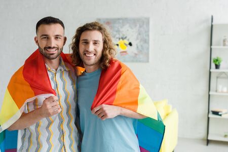 happy homosexual men holding lgbt flag and looking at cameraの写真素材