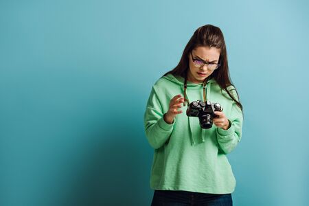 serious photographer looking at digital camera on blue backgroundの写真素材