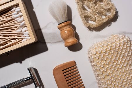 Top view of comb, razor, sponges, box of ear sticks and shaving brush on white background, zero...