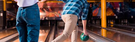 cropped view of girl standing near man throwing bowling ball on skittle alley, panoramic shotの写真素材