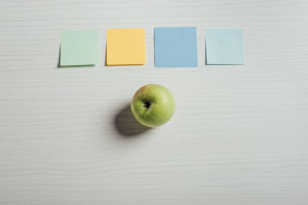 top view of green apple and empty note stickers on table