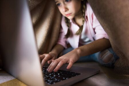 selective focus of frustrated kid covered in blanket typing on laptop keyboard, cyberbullying...