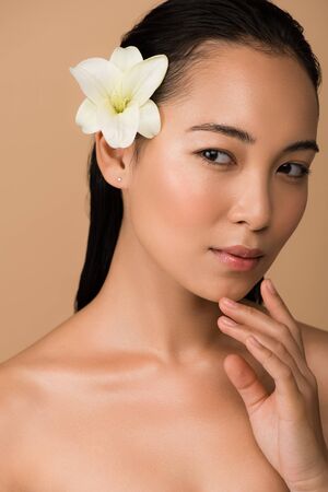 beautiful asian girl with white lily in hair isolated on beige