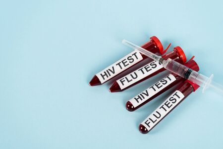 top view of syringe on samples with hiv test and flu test lettering on blueの写真素材