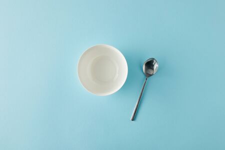Top view of empty bowl and spoon on blue backgroundの写真素材
