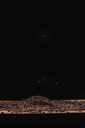 roasted coffee beans in pile isolated on blackの写真素材