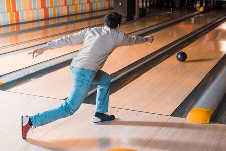 back view of young man throwing bowling ball on skittle alleyの写真素材