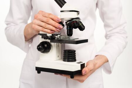 cropped view of scientist in white coat holding microscope isolated on whiteの写真素材