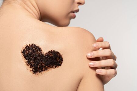 partial view of girl with heart sign of coffee scrub on body, isolated on grey