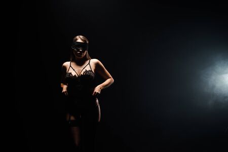 submissive and blindfolded girl in underwear standing on black with smoke