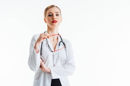 sexy nurse holding glasses and looking at camera isolated on whiteの写真素材