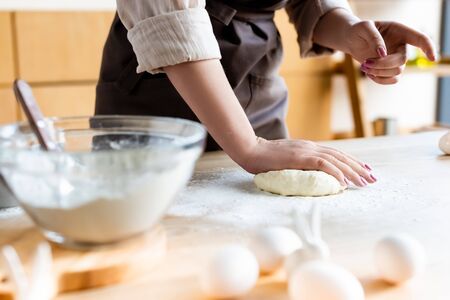 selective focus of woman in apron kneading dough