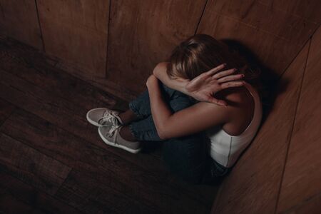 High angle view of victim with obscure face showing stop and sitting in cornerの写真素材