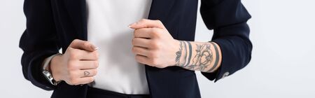 cropped view of successful young tattooed businesswoman with hands on blazer isolated on white, panoramic shotの写真素材