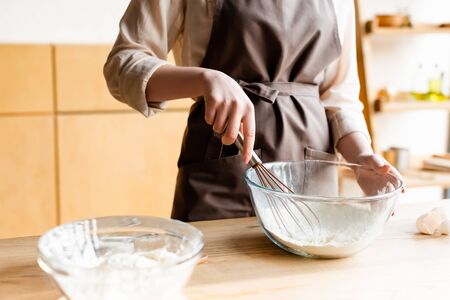 cropped view of girl holding whisk near bowl with flourの写真素材