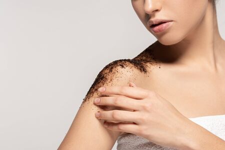 cropped view of girl applying coffee exfoliant on shoulders, isolated on greyの写真素材