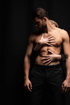 young woman touching sexy man isolated on blackの写真素材