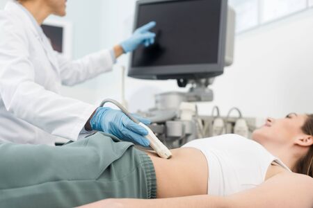 cropped view of doctor making ultrasound scan of stomach and pointing at blank screen