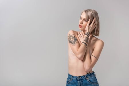 sexy young topless tattooed woman posing isolated on greyの写真素材