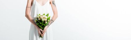cropped view of tattooed bride with floral bouquet on white, panoramic shot