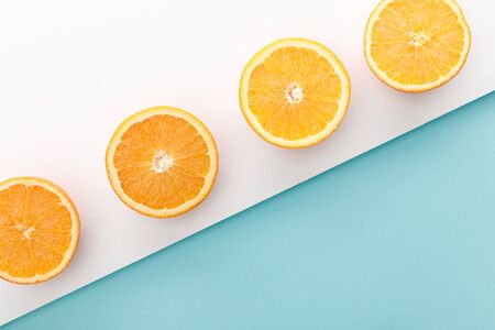 Top view of cut oranges on white and blue background
