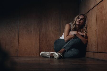 Victim with crossed arms sitting on floorの写真素材