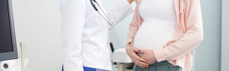 panoramic shot of pregnant woman having consultation with doctor in gynecological clinicの写真素材