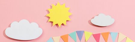 Top view of paper cut sun, clouds and flags on pink background, panoramic shotの写真素材