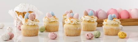 Delicious cupcakes with colorful painted chicken and quail eggs near easter cake on grey background,...