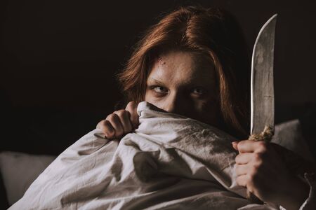 demonic obsessed evil girl holding knife in bedの写真素材