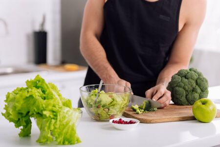 cropped view of man cutting broccoli on chopping boardの写真素材