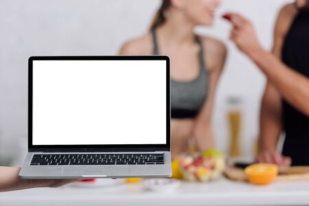selective focus of laptop with white screen near couple in kitchenの写真素材