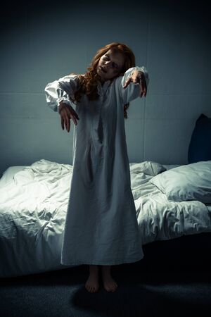 creepy demonic woman in nightgown standing in bedroomの写真素材