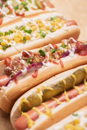 selective focus of fresh various delicious hot dogs with vegetables and sauces on wooden tableの写真素材