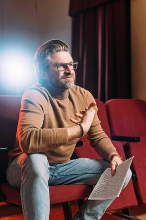emotional stage director with scenario on seats in theater with backlight