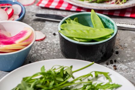 selective focus of fresh radish salad ingredients in bowls on grey concrete surfaceの写真素材